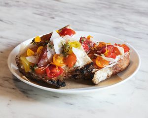 Juicy peak-season tomatoes on artisan sourdough toast at sustainable restaurant Lula Cafe in Chicago, IL