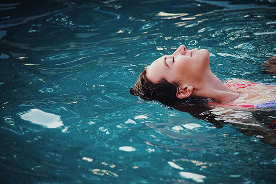 Woman mindfully and joyfully relaxing in a pool